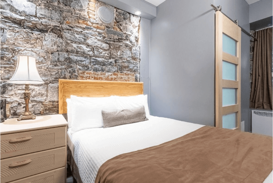 Chambre avec mur de pierre et lit queen à l’Hôtel Jardin du Gouverneur, Vieux-Québec